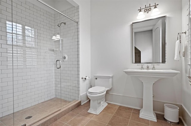 full bathroom with toilet, a stall shower, tile patterned floors, and baseboards