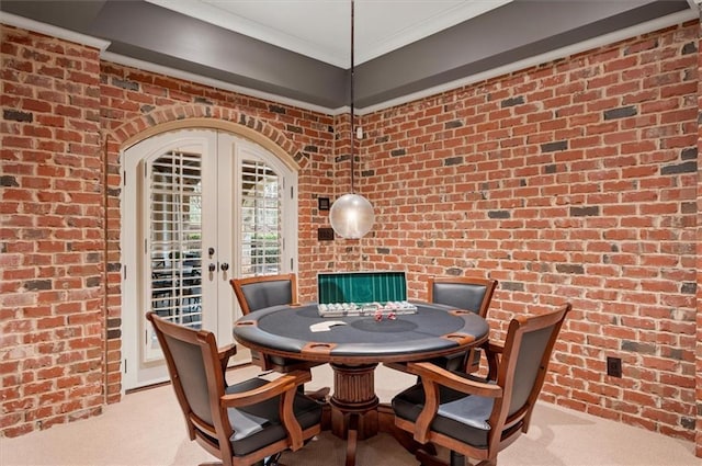 carpeted dining space with brick wall, ornamental molding, and french doors