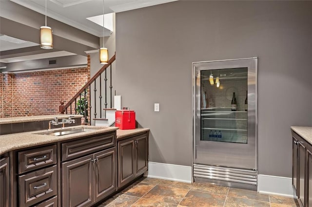 kitchen with refrigerator, baseboards, a sink, ornamental molding, and decorative light fixtures