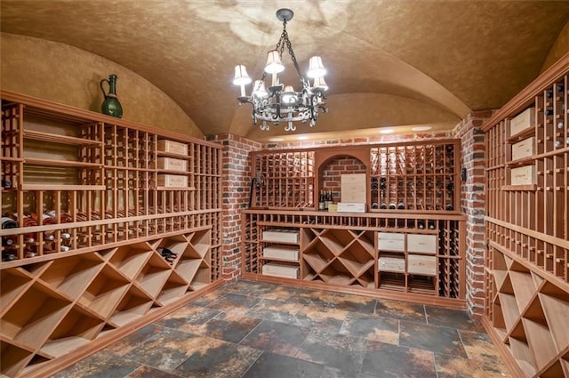 wine area with lofted ceiling, stone tile flooring, and a chandelier
