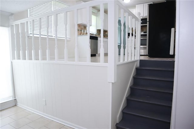 stairway with wooden walls and tile patterned flooring