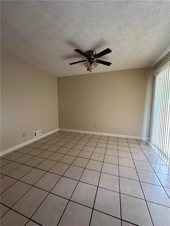 213 Peartree Ln, Riverdale, GA 30274 - empty room featuring a ceiling fan, a textured ceiling, light tile patterned flooring, and baseboards