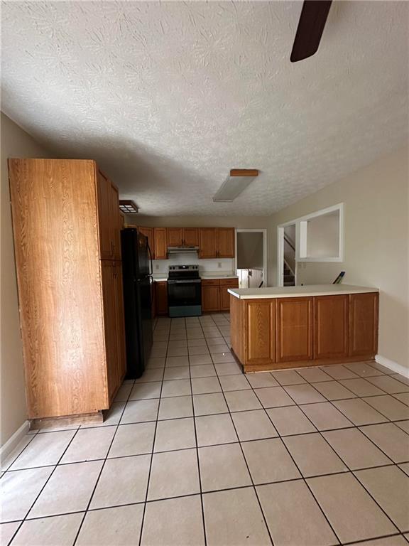 213 Peartree Ln, Riverdale, GA 30274 - kitchen with electric stove, freestanding refrigerator, a peninsula, light countertops, and brown cabinetry