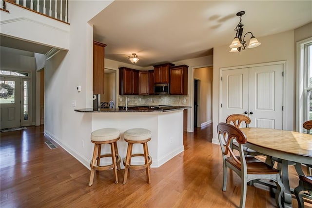 kitchen featuring hardwood / wood-style flooring, decorative backsplash, pendant lighting, and kitchen peninsula