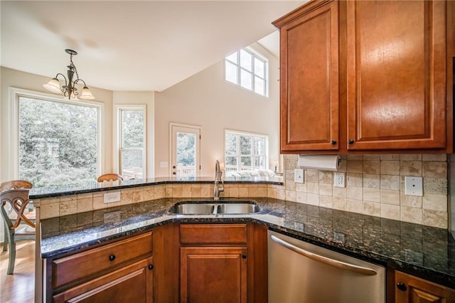 kitchen featuring stainless steel dishwasher, a wealth of natural light, sink, and a notable chandelier