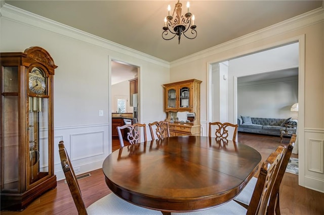 dining room featuring dark hardwood / wood-style flooring, a chandelier, and crown molding