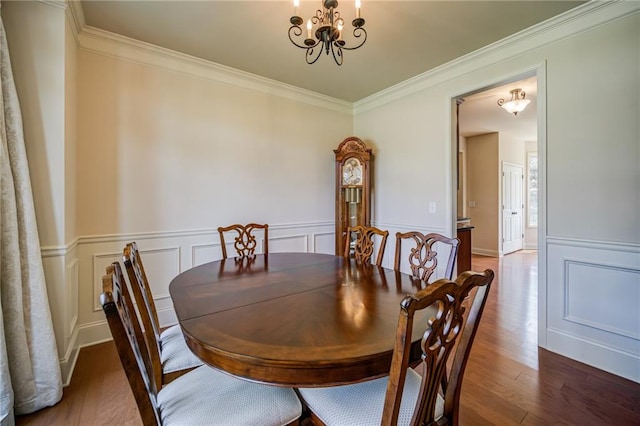 dining space featuring dark wood-type flooring, a chandelier, and crown molding