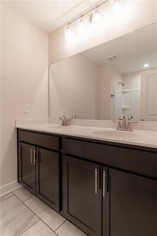 bathroom featuring tile patterned flooring, vanity, and a shower