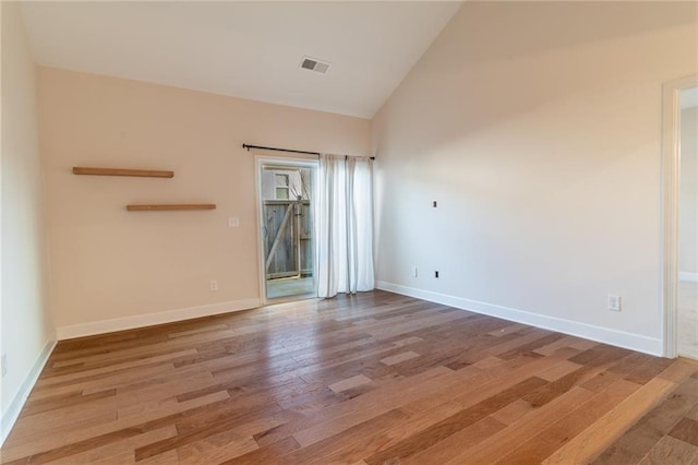 spare room with hardwood / wood-style floors and high vaulted ceiling