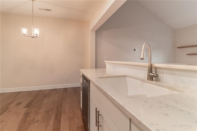 kitchen featuring dark hardwood / wood-style floors, hanging light fixtures, sink, white cabinets, and stainless steel dishwasher