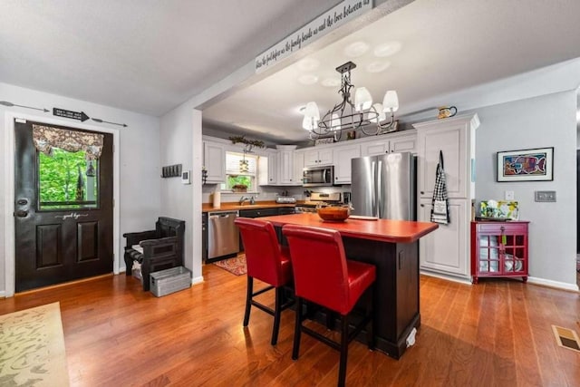 kitchen with butcher block countertops, light hardwood / wood-style floors, stainless steel appliances, and white cabinets