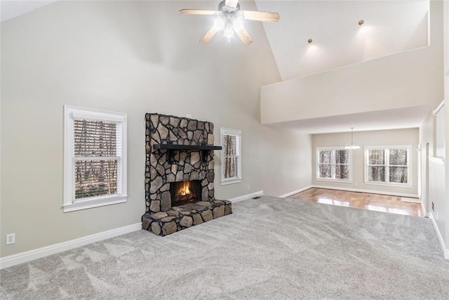 living area featuring baseboards, carpet floors, a fireplace, high vaulted ceiling, and ceiling fan with notable chandelier