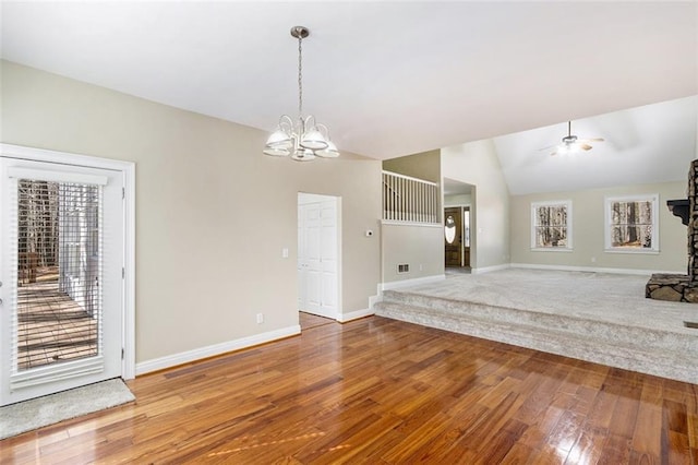 interior space featuring lofted ceiling, ceiling fan with notable chandelier, wood finished floors, and baseboards