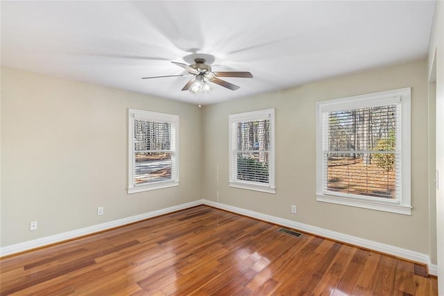 spare room with a ceiling fan, baseboards, visible vents, and wood finished floors