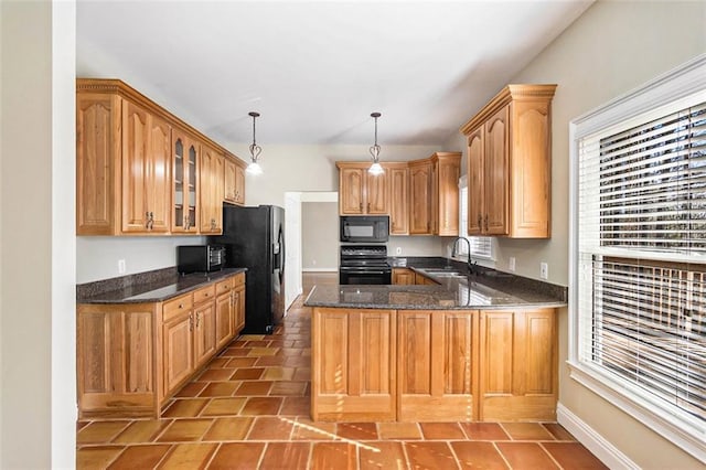 kitchen with glass insert cabinets, a peninsula, black appliances, pendant lighting, and a sink