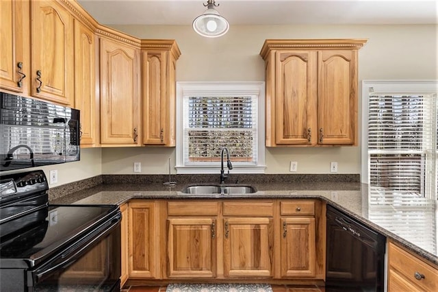 kitchen with black appliances, dark stone countertops, a sink, and pendant lighting