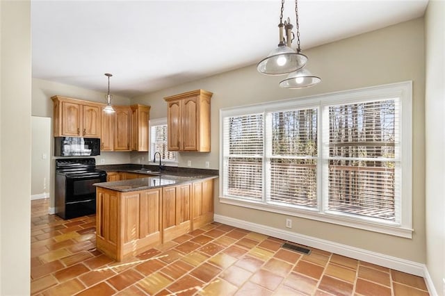 kitchen with a sink, visible vents, baseboards, hanging light fixtures, and black appliances