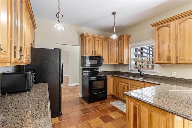 kitchen featuring dark stone counters, a sink, hanging light fixtures, and black appliances