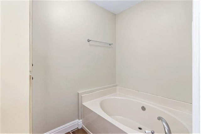 full bathroom with a bath and baseboards