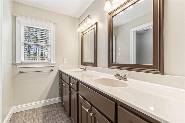 bathroom with a sink, baseboards, and double vanity