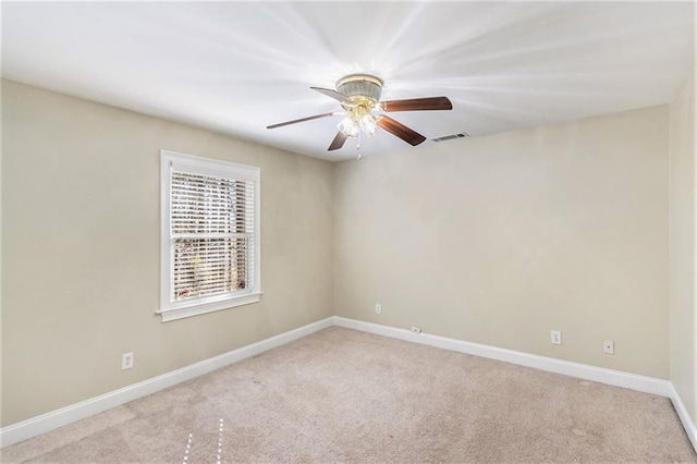 carpeted empty room featuring a ceiling fan, visible vents, and baseboards