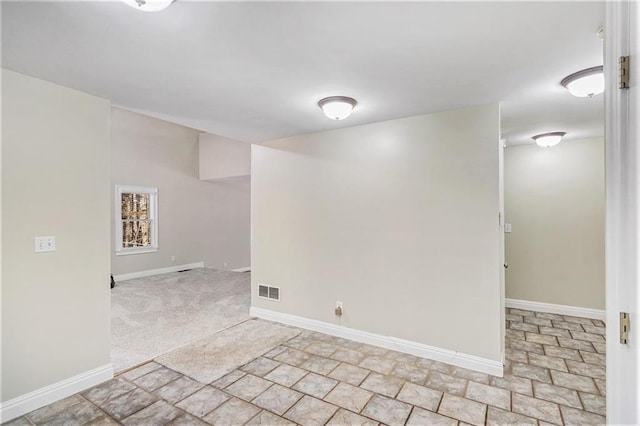 empty room featuring light carpet, visible vents, and baseboards