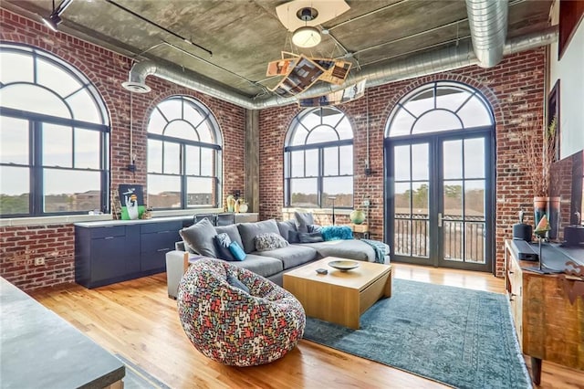 living room with brick wall, light hardwood / wood-style flooring, and a high ceiling