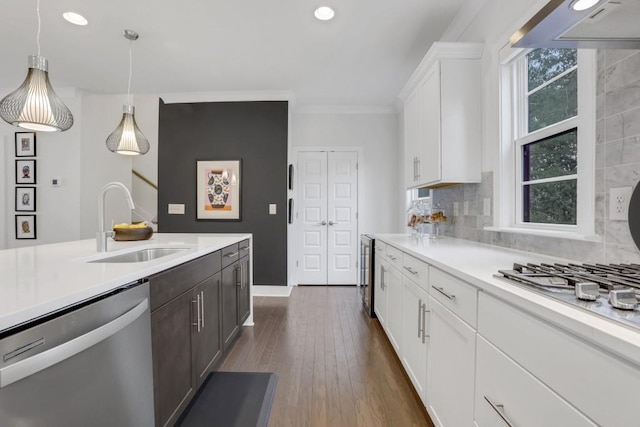 kitchen featuring appliances with stainless steel finishes, decorative light fixtures, tasteful backsplash, white cabinetry, and sink