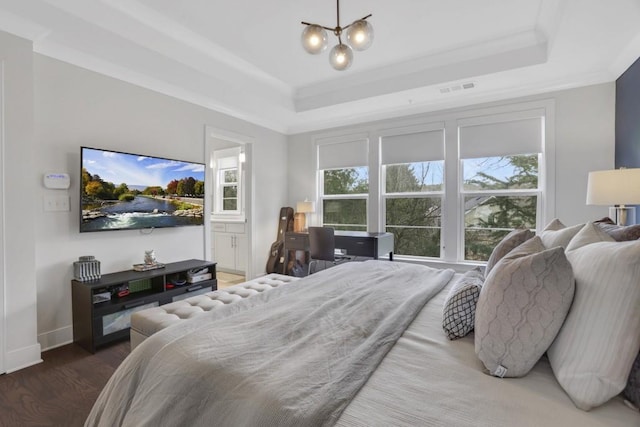 bedroom featuring ensuite bathroom, a chandelier, dark hardwood / wood-style flooring, a tray ceiling, and crown molding