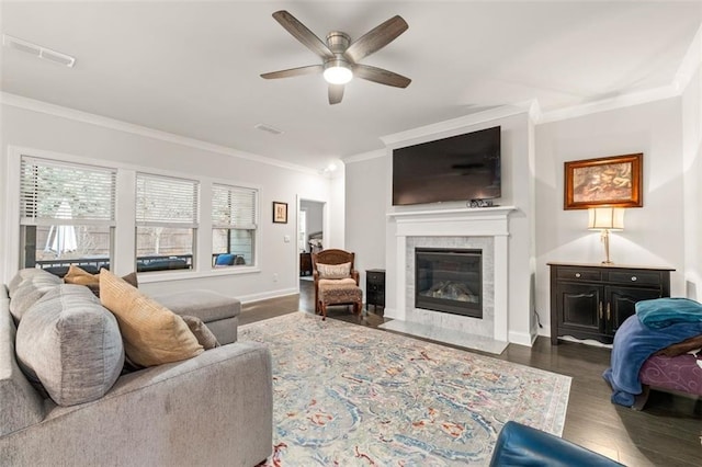 living room with a fireplace, crown molding, dark wood-type flooring, and ceiling fan