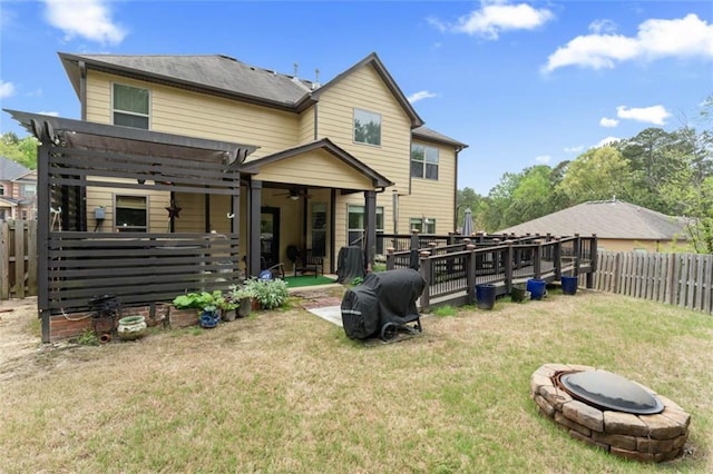 back of house with a pergola, a lawn, and a fire pit