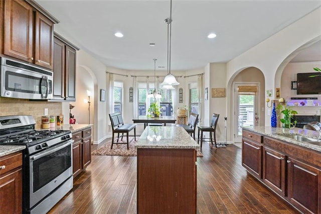 kitchen featuring a center island, appliances with stainless steel finishes, dark wood-type flooring, and pendant lighting