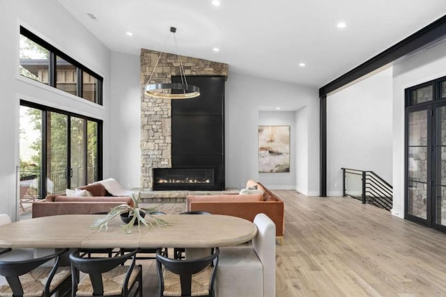 interior space with vaulted ceiling, a stone fireplace, and light hardwood / wood-style floors