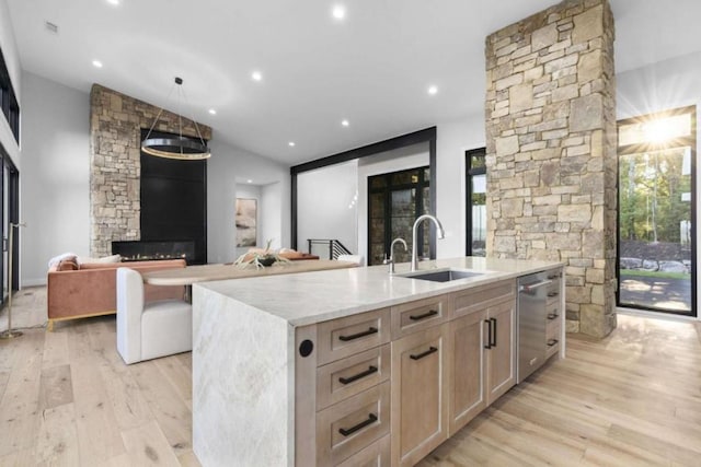 kitchen featuring sink, light hardwood / wood-style floors, light stone countertops, a center island with sink, and light brown cabinets