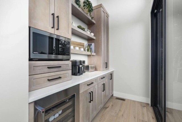 bar featuring wine cooler, light brown cabinetry, and light hardwood / wood-style floors