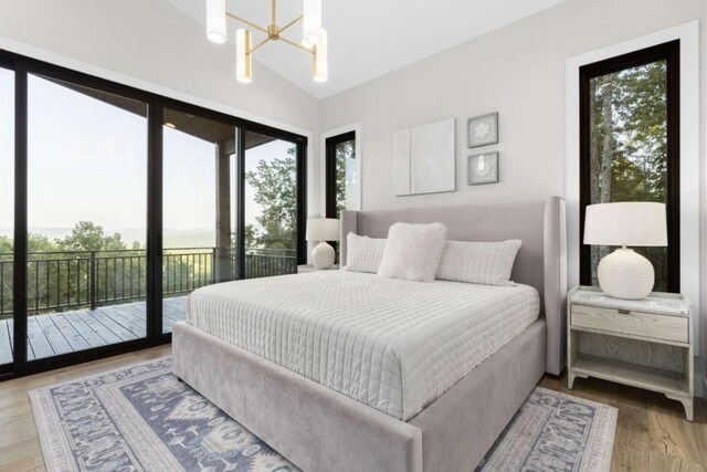 bedroom with vaulted ceiling, a notable chandelier, light wood-type flooring, and access to outside