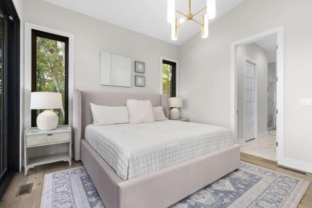 bedroom featuring vaulted ceiling, a chandelier, and light wood-type flooring