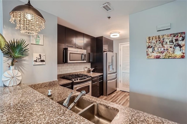 3338 Peachtree Rd NE Unit 1507, Atlanta, GA 30326 - kitchen featuring stainless steel appliances, light wood-type flooring, backsplash, pendant lighting, and a chandelier