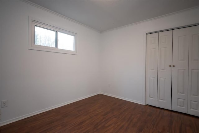 unfurnished bedroom featuring ornamental molding, dark wood-type flooring, and a closet