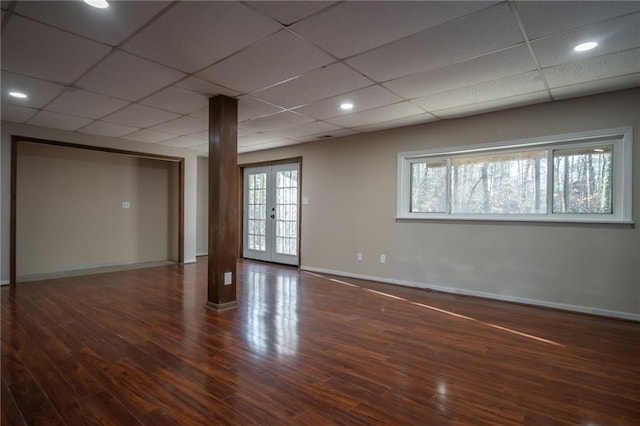 basement featuring dark hardwood / wood-style floors, a paneled ceiling, and french doors