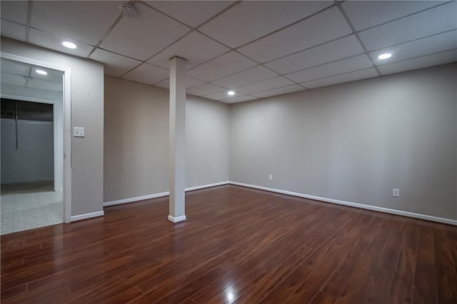 basement featuring dark wood-type flooring and a drop ceiling