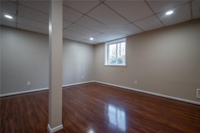 basement with a drop ceiling and dark wood-type flooring