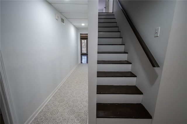 stairway featuring a drop ceiling