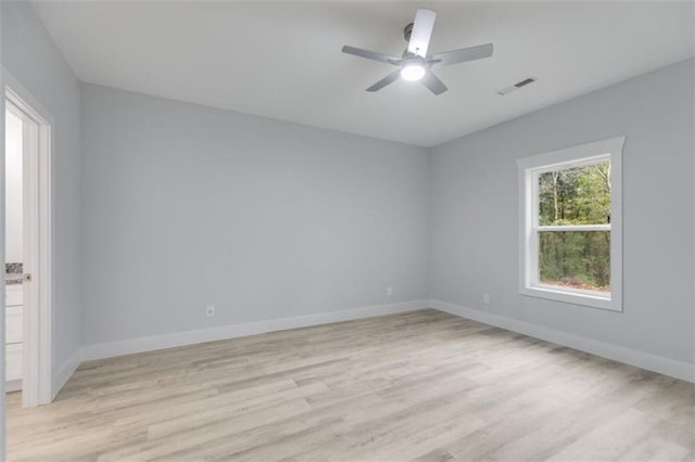 empty room featuring ceiling fan, light wood-type flooring, visible vents, and baseboards