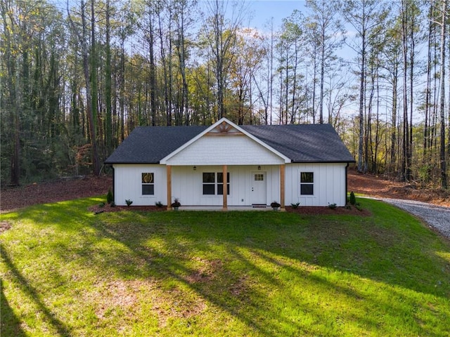 modern farmhouse with board and batten siding, a front yard, and a wooded view