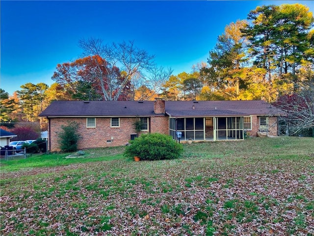 rear view of property with a sunroom and a lawn