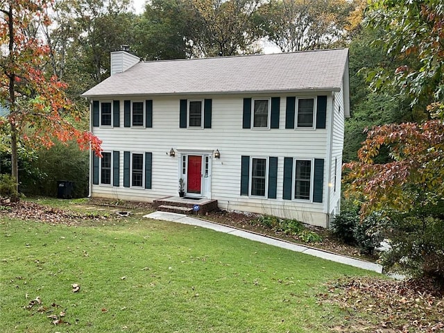 colonial inspired home featuring a chimney and a front yard