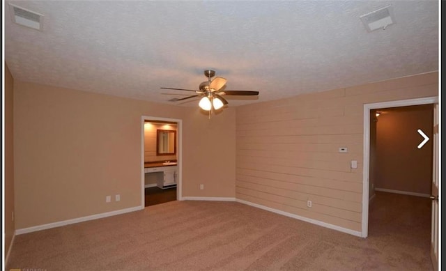 carpeted spare room with baseboards, visible vents, and a textured ceiling