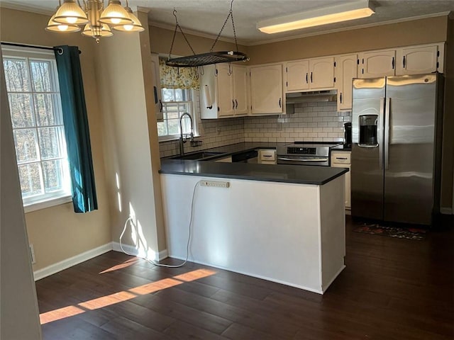 kitchen featuring under cabinet range hood, dark wood-style flooring, a sink, appliances with stainless steel finishes, and dark countertops