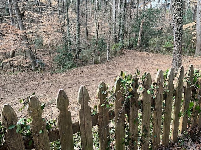 view of yard with a wooded view and fence